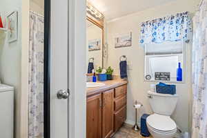 Full bathroom featuring a shower with shower curtain, vanity, washer / dryer, and light tile patterned floors