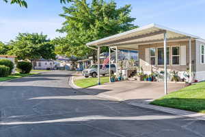 View of front of property featuring concrete driveway, a carport, a front lawn, and a residential view