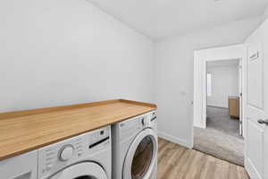 Laundry room featuring washing machine and clothes dryer and light wood-type flooring