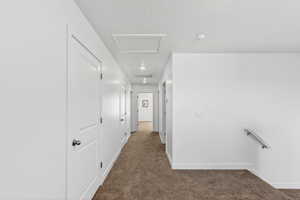 Hall featuring dark carpet and attic access