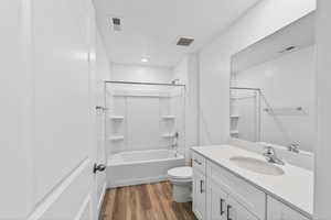 Bathroom with vanity, washtub / shower combination, and dark wood finished floors