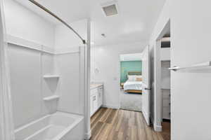 Ensuite bathroom with vanity, light wood-type flooring, and shower / tub combination