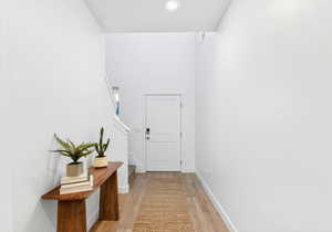 Entryway with wood finished floors, a towering ceiling, and recessed lighting