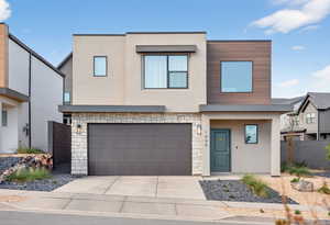 Contemporary home featuring stone siding, stucco siding, an attached garage, and driveway