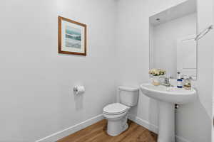Half bathroom with toilet and wood finished floors