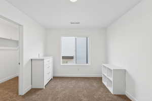 Unfurnished bedroom with dark colored carpet and a spacious closet
