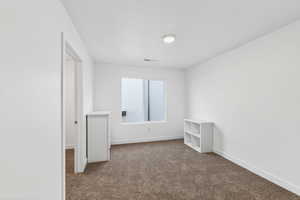 Unfurnished room featuring dark carpet and baseboards