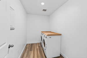 Washroom with dark wood-style floors and independent washer and dryer