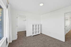 Unfurnished bedroom featuring dark colored carpet and a spacious closet