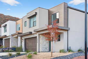 Modern home with stone siding, stucco siding, and a garage