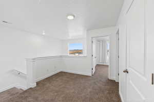 Unfurnished room with dark colored carpet and a textured ceiling