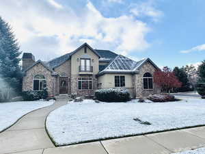 French country inspired facade featuring stucco siding, a chimney, a balcony, and french doors
