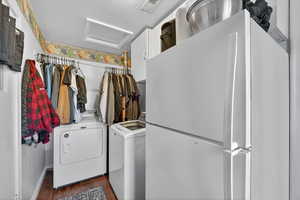 Laundry room with attic access, washer and dryer, and dark wood-type flooring