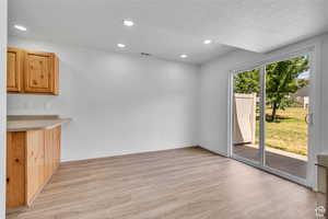 Unfurnished dining area featuring light wood-style flooring, recessed lighting, and a textured ceiling