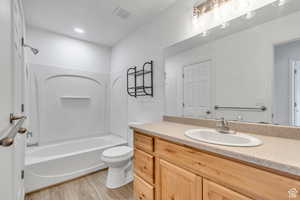 Full bath with shower / bath combination, vanity, and light wood finished floors
