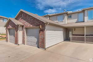 View of front of home featuring brick siding, roof with shingles, an attached garage, and concrete driveway