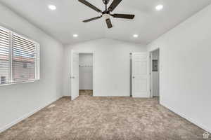 Unfurnished bedroom featuring a spacious closet, lofted ceiling, light carpet, ceiling fan, and electric panel