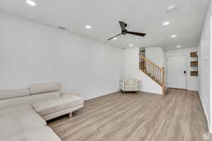 Living room featuring recessed lighting, stairway, light wood-style flooring, and ceiling fan