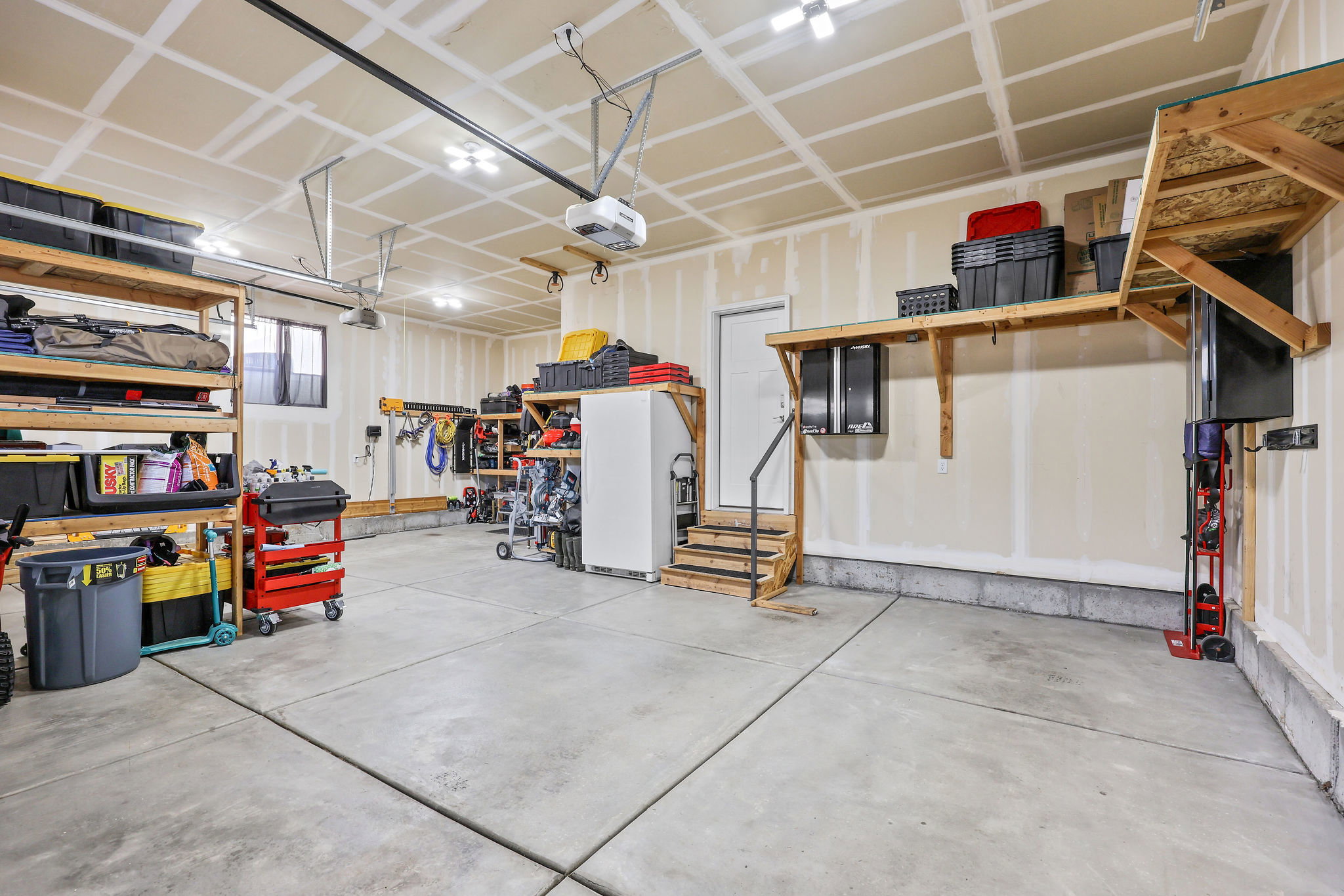 Garage featuring freestanding refrigerator and a garage door opener