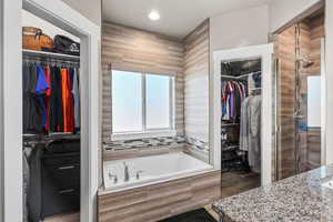 Bathroom featuring a spacious closet, a garden tub, a shower stall, vanity, and recessed lighting