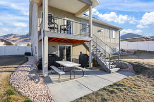 Rear view of property featuring a patio, a fenced backyard, stairs, stucco siding, and a balcony