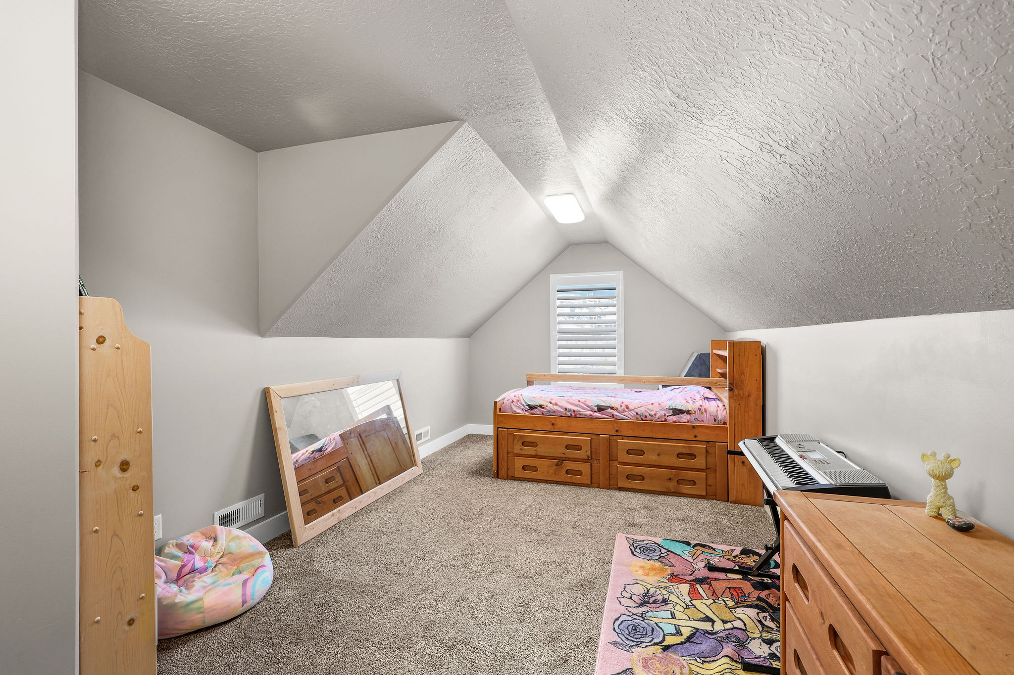 Bedroom with light colored carpet, a textured ceiling, and vaulted ceiling