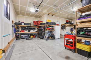 Garage with a workshop area, freestanding refrigerator, and a garage door opener