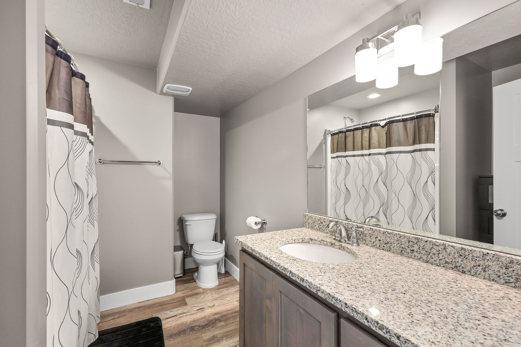 Bathroom featuring curtained shower, vanity, light wood-style flooring, and a textured ceiling