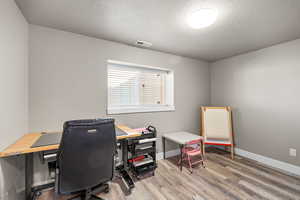 Home office with a textured ceiling and light wood-type flooring
