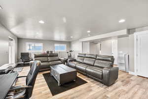 Living area with recessed lighting, light wood-style flooring, and a textured ceiling