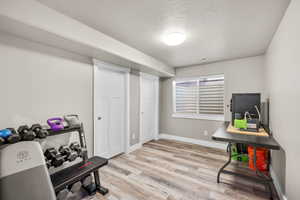 Workout room with a textured ceiling and light wood finished floors