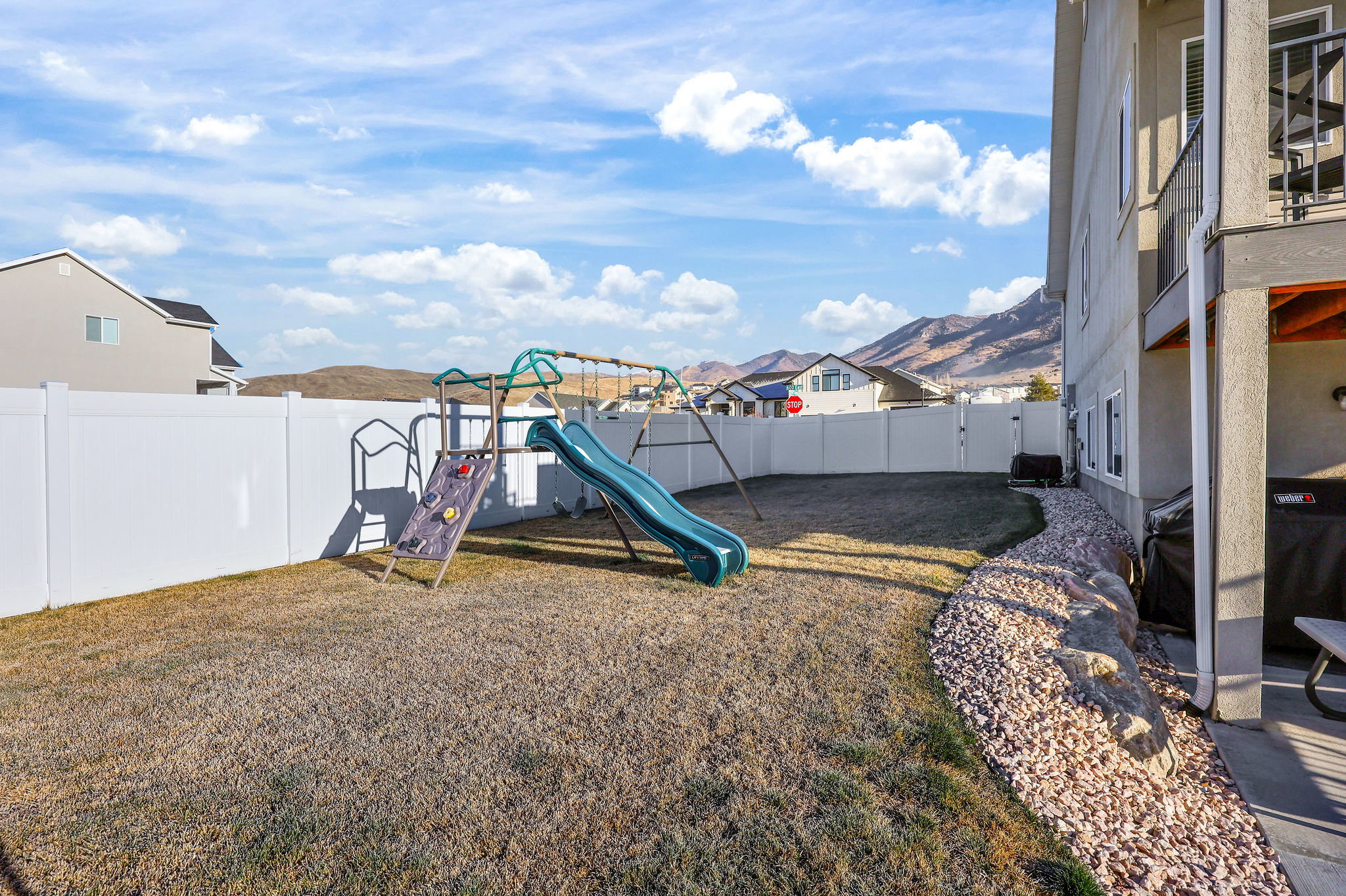Fenced backyard featuring a playground and a residential view