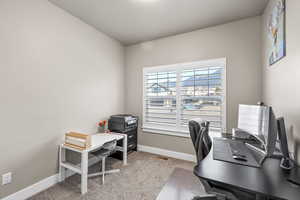 Home office with baseboards and light carpet