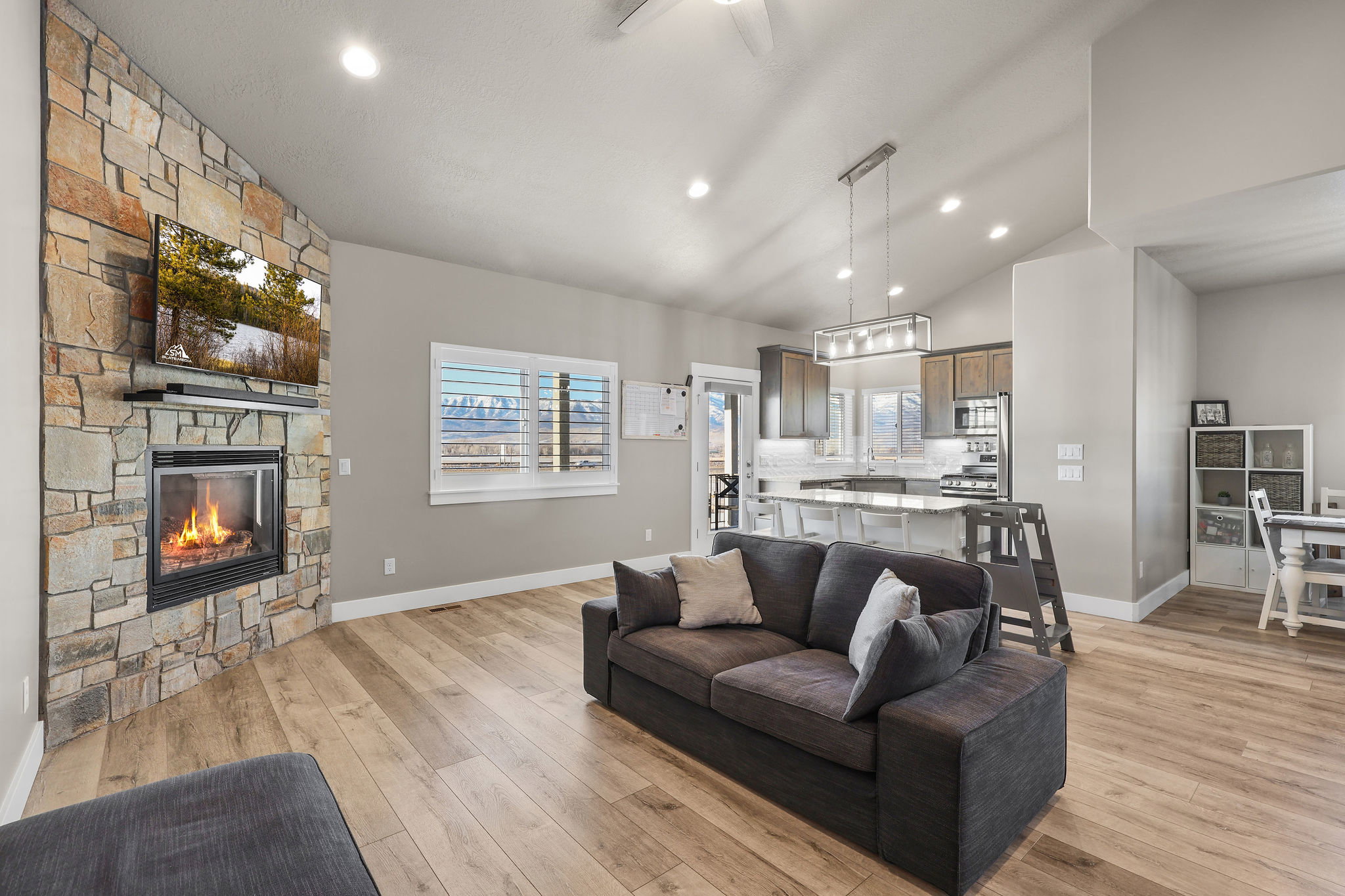 Living area with light wood-style flooring, recessed lighting, a stone fireplace, and lofted ceiling