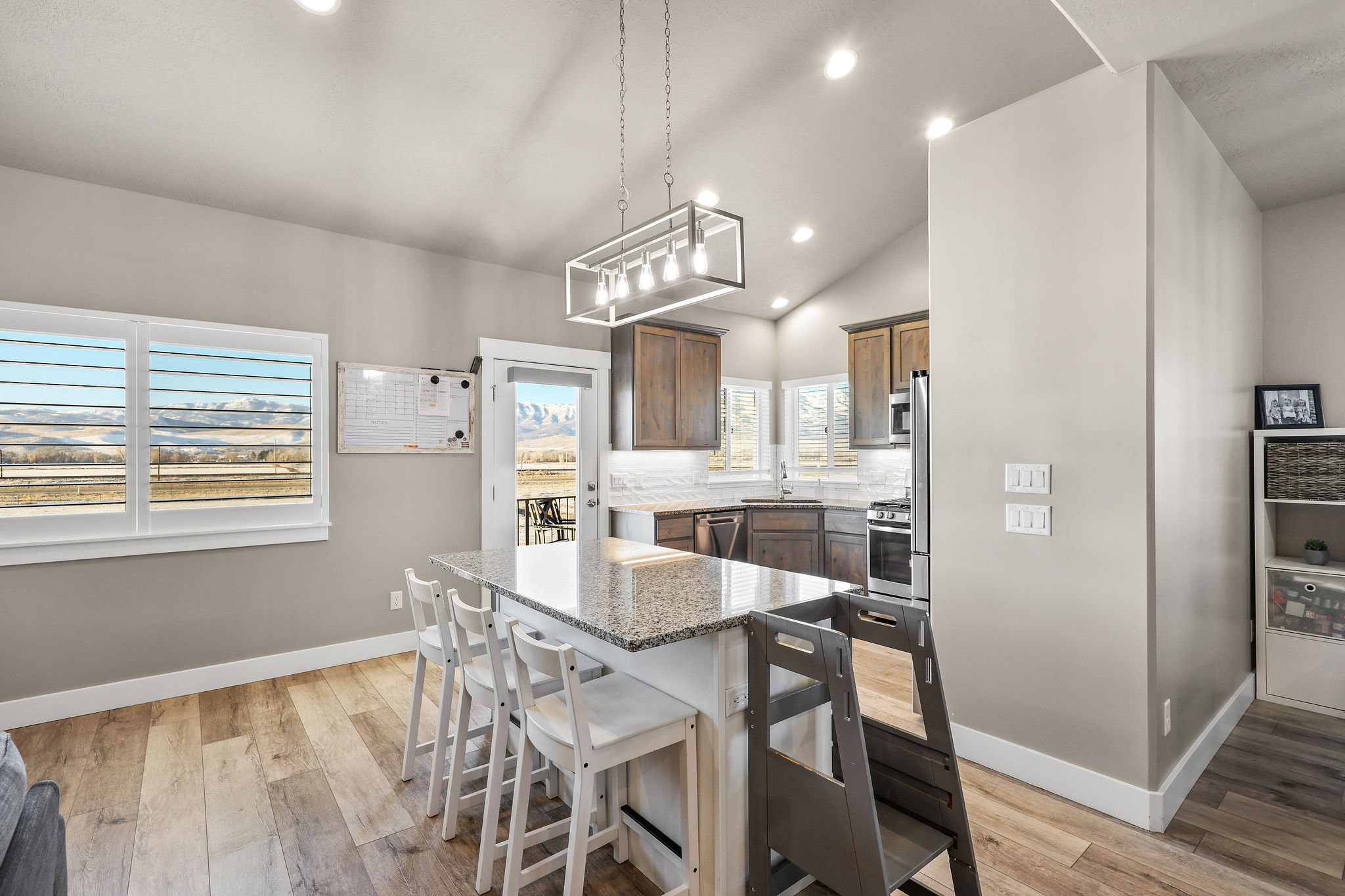 Kitchen featuring vaulted ceiling, light stone counters, a kitchen breakfast bar, recessed lighting, and a kitchen island