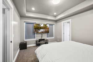 Carpeted bedroom with a tray ceiling, recessed lighting, and a textured ceiling