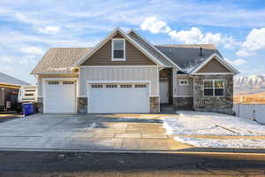 Craftsman-style home featuring board and batten siding, stone siding, concrete driveway, a garage, and a mountain view
