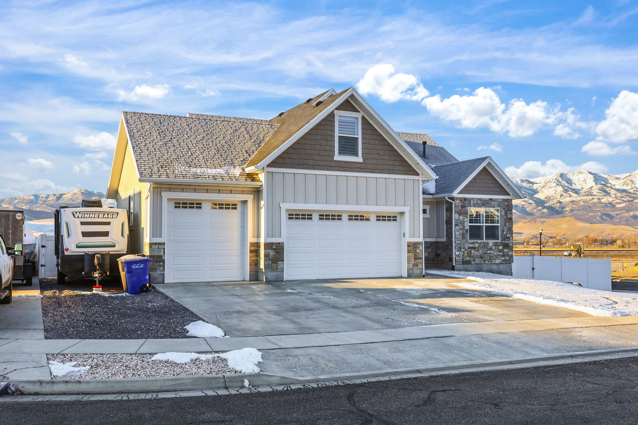 Craftsman-style house featuring a mountain view, board and batten siding, driveway, and stone siding