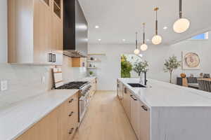 Kitchen featuring light brown cabinets, light stone counters, hanging light fixtures, and recessed lighting