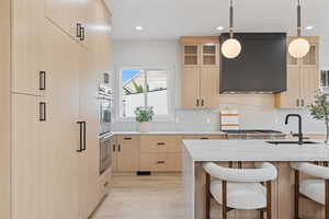 Kitchen featuring light brown cabinets, light stone countertops, a breakfast bar, hanging light fixtures, and recessed lighting
