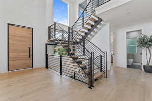 Stairs featuring healthy amount of natural light, hardwood / wood-style floors, and a high ceiling