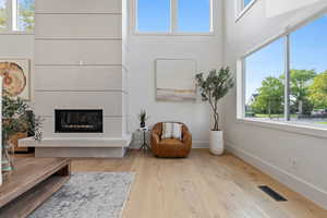 Sitting room featuring a glass covered fireplace, a high ceiling, and wood-type flooring