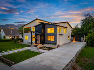 Contemporary home with concrete driveway, a front lawn, an outdoor structure, stucco siding, and a mountain view