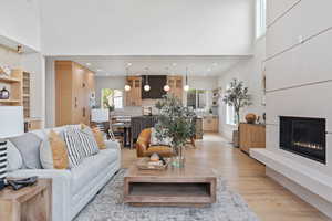 Living area with a towering ceiling, light wood-style flooring, and a glass covered fireplace