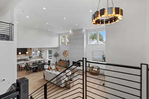 Living room featuring a towering ceiling, light wood finished floors, and recessed lighting