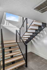 Stairway featuring baseboards and a textured ceiling