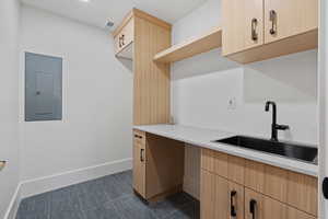 Laundry area with electric panel and baseboards