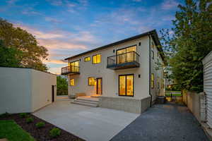 Back of property at dusk with a patio, a balcony, and stucco siding