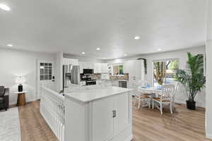 Kitchen featuring white cabinetry, appliances with stainless steel finishes, recessed lighting, a center island, and light wood finished floors
