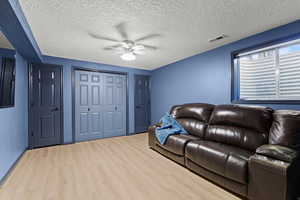 Living room featuring a textured ceiling, wood finished floors, and a ceiling fan